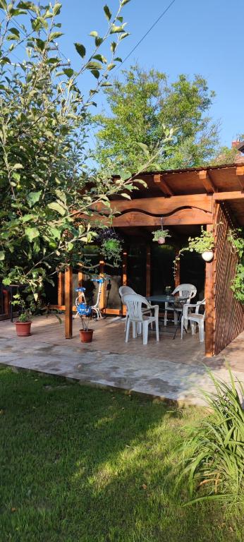 un patio de madera con sillas blancas y una mesa en Casa M, en Câmpulung Moldovenesc
