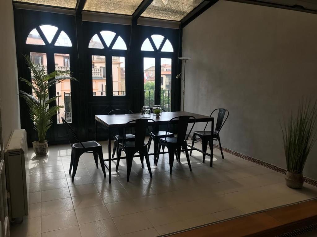 Un comedor con mesa y sillas y ventanas. en Corrillo Suite Plaza Mayor - Parking opcional, en Salamanca