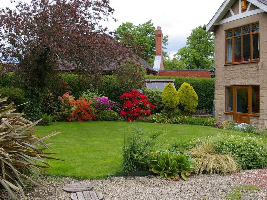 a yard with green grass and flowers and a house at The Grange in Normanton