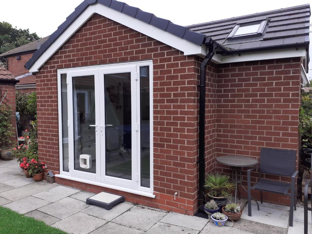 a garden room with a sliding glass door at Rose View- a lovely private 1 Bed Bungalow in Sale in Sale