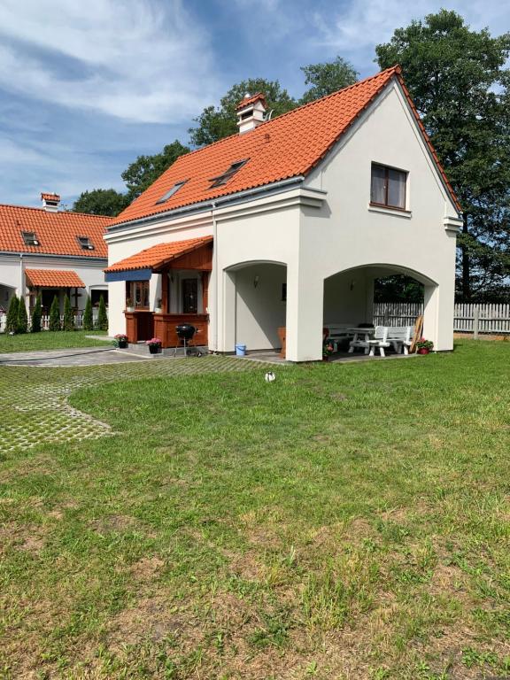 a large white house with an orange roof at Słoneczne Wrota in Pisz