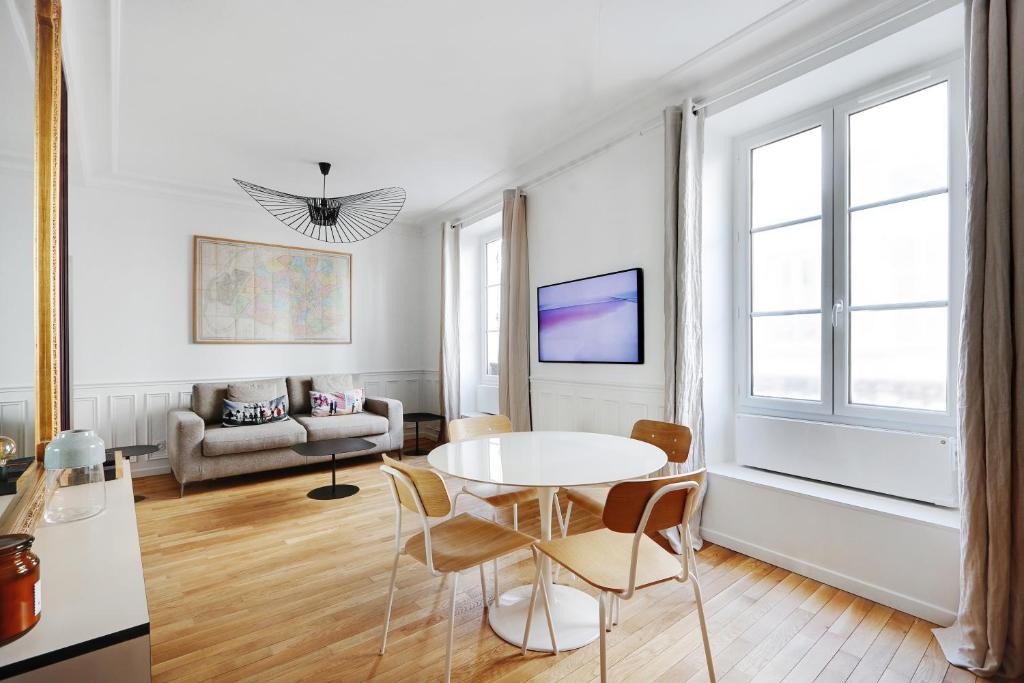 a white living room with a table and chairs at Pick A Flat's Apartment in Marais/Oberkampf - bvd du Temple in Paris