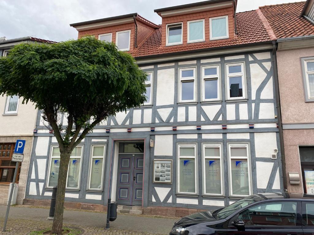 un edificio blanco y negro con un árbol delante en Passage 84 - Hotel & Café, en Heilbad Heiligenstadt