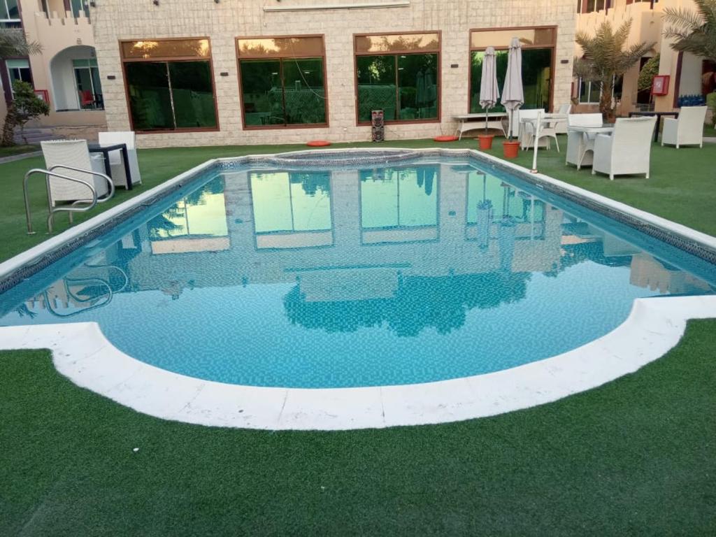 Corniche Palace Hotel في عجمان: مسبح بمياه زرقاء امام مبنى