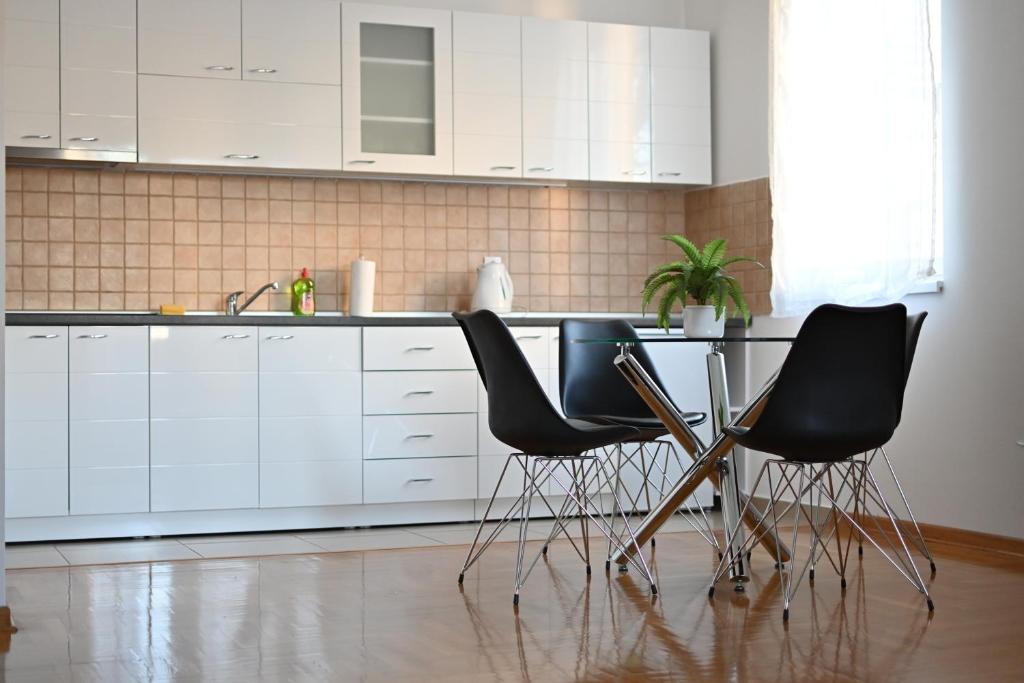 una cocina con sillas negras y una mesa. en New Apartment CRISTAL in the city centre en Novi Sad