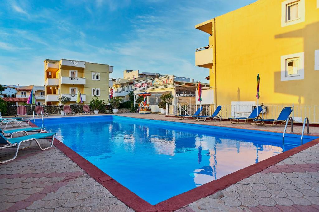 a swimming pool in a resort with chairs and buildings at Irini Stalis by Estia in Stalida