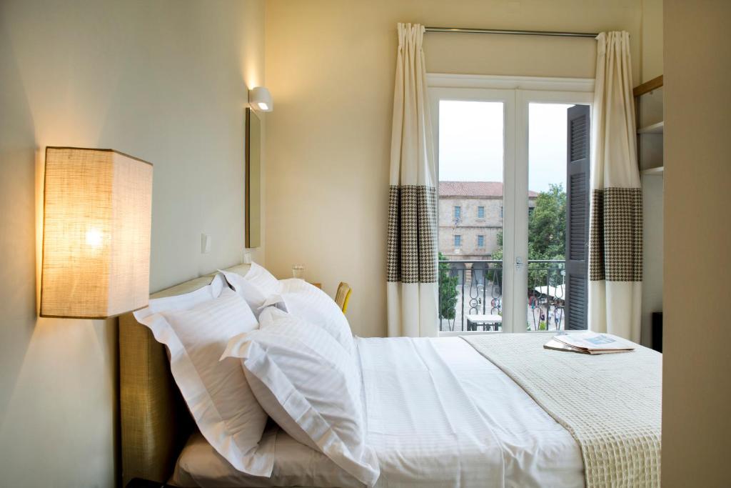 1 dormitorio con cama blanca y ventana en Athena hotel, en Nauplia