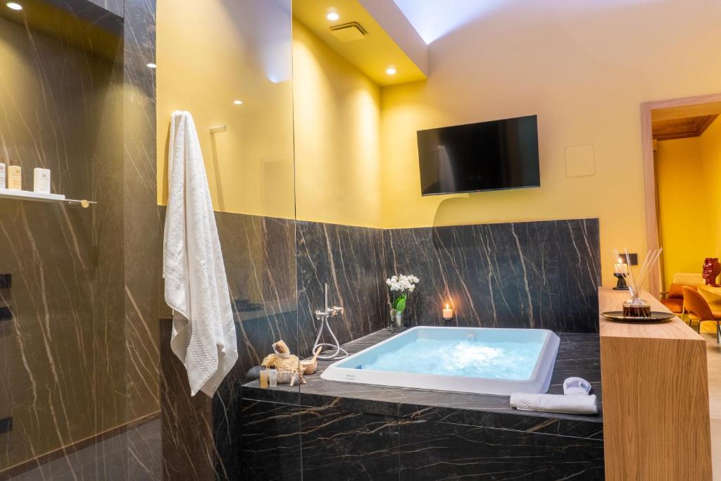 a bathroom with a tub and a tv on the wall at ETNEA Suite 270 in Catania