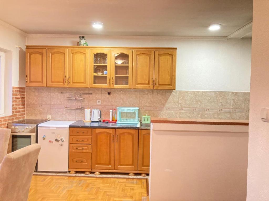 a kitchen with wooden cabinets and a white refrigerator at Guest House Nena in Žabljak