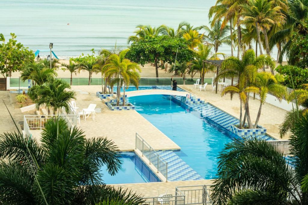 - une vue aérienne sur la piscine du complexe bordée de palmiers et l'océan dans l'établissement Magico Apartamento Frente al Mar 3 Habitaciones AR33, à Coveñas
