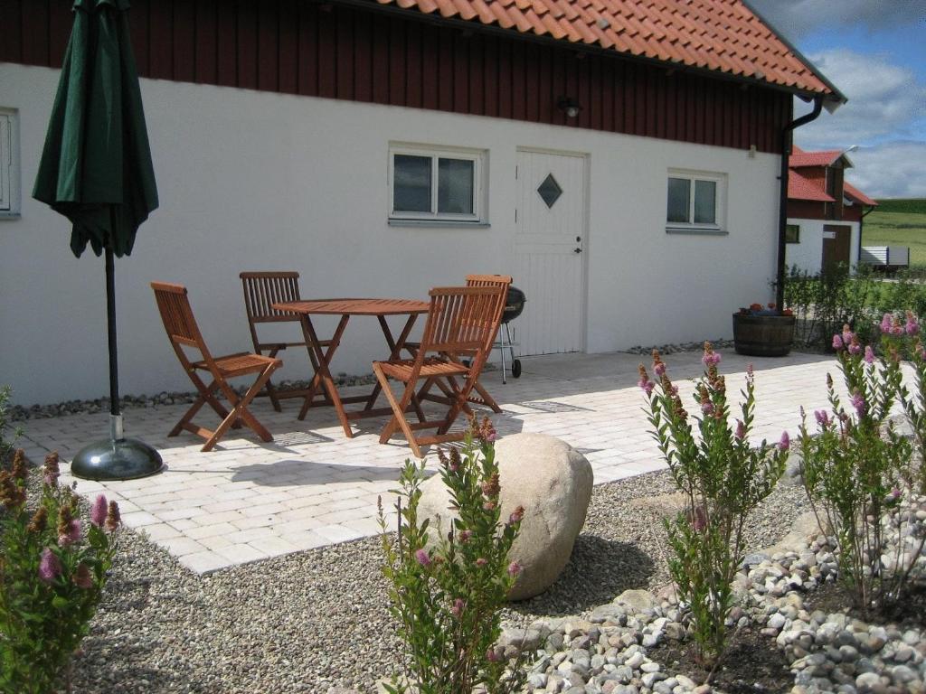 een patio met een tafel en stoelen en een parasol bij Gårdsboende in Skårby