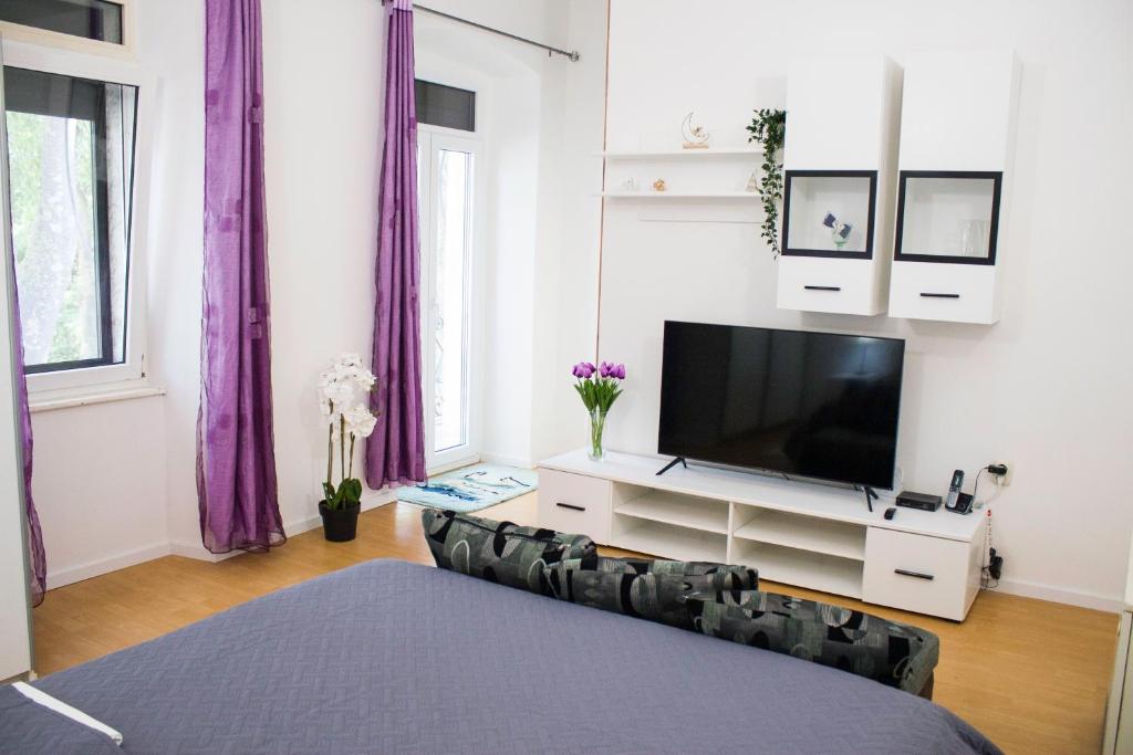 a living room with a television and purple curtains at White Orchid Pula in Pula