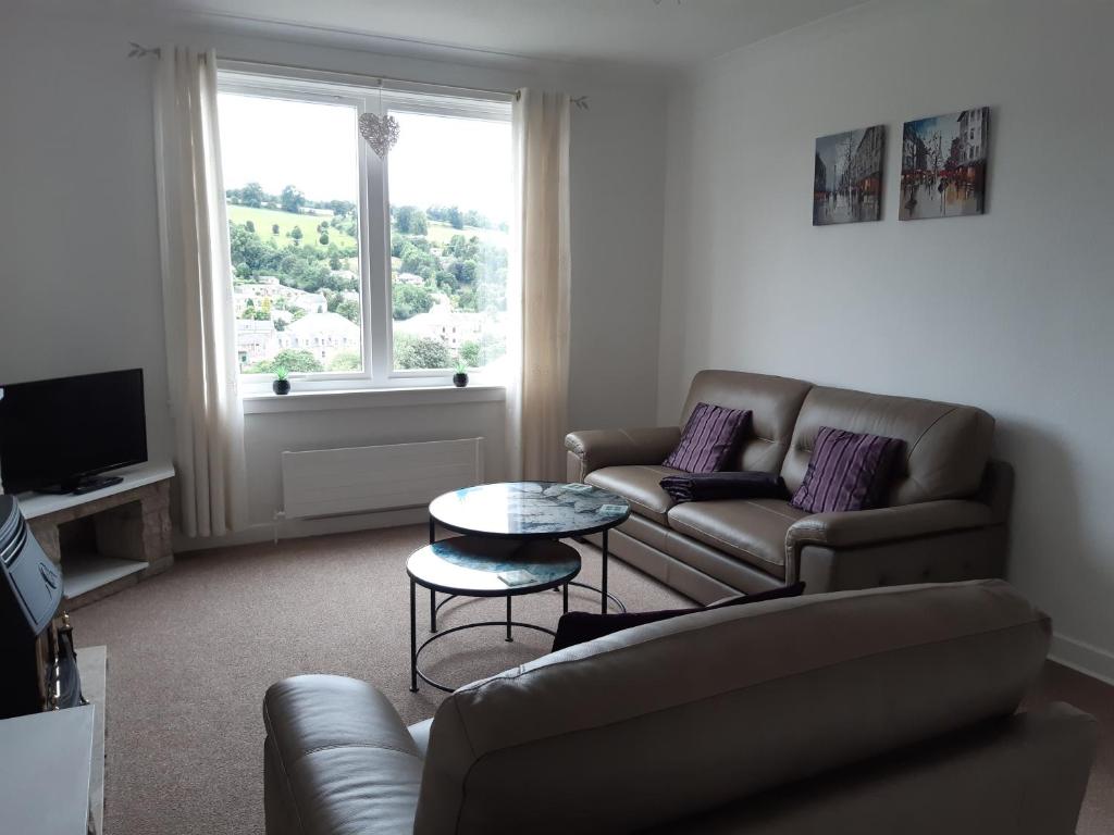 uma sala de estar com um sofá e uma mesa em Self contained apartment with amazing views em Jedburgh