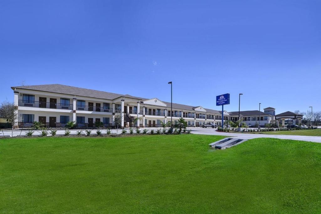a large building with a green lawn in front of it at Americas Best Value Inn Cuero in Cuero