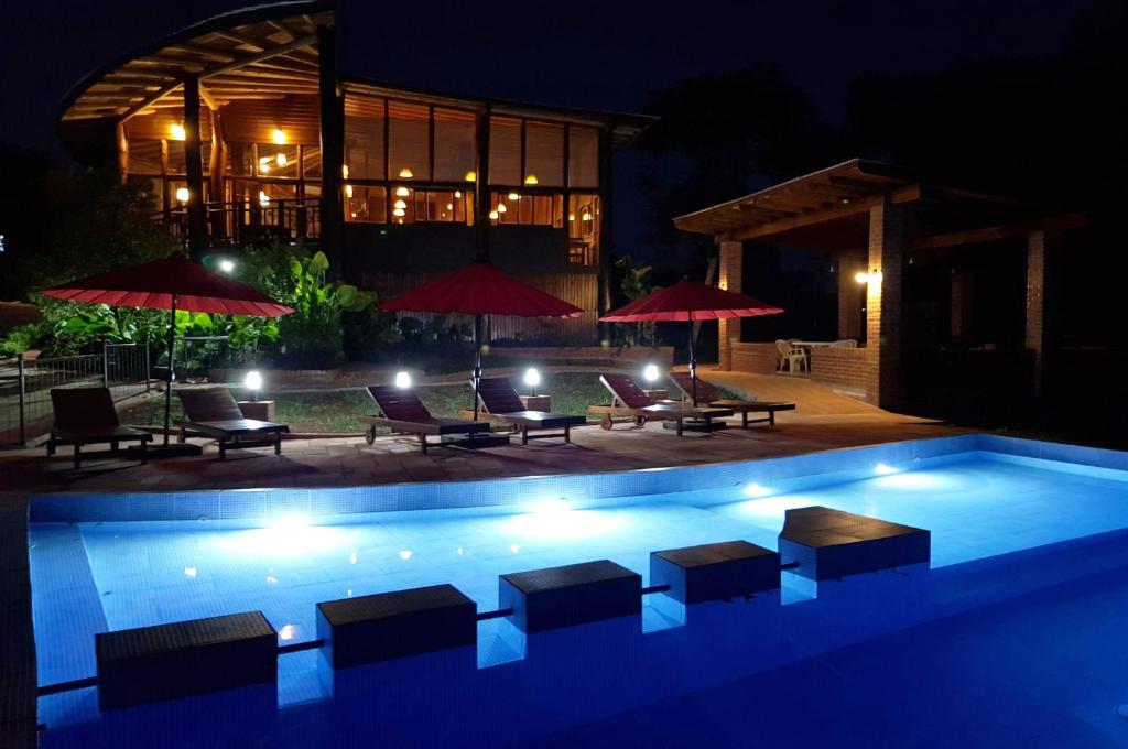 a swimming pool at night with chairs and umbrellas at Puro Moconá Lodge in El Soberbio