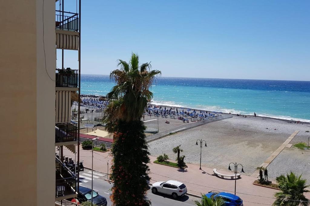 a view of a beach with a palm tree and the ocean at Casalmare Sabina in Ventimiglia