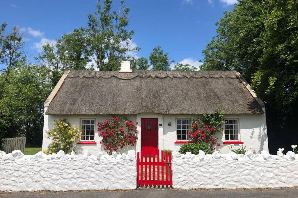 een klein wit huis met een rieten dak bij Clannad Cottage in Arboe
