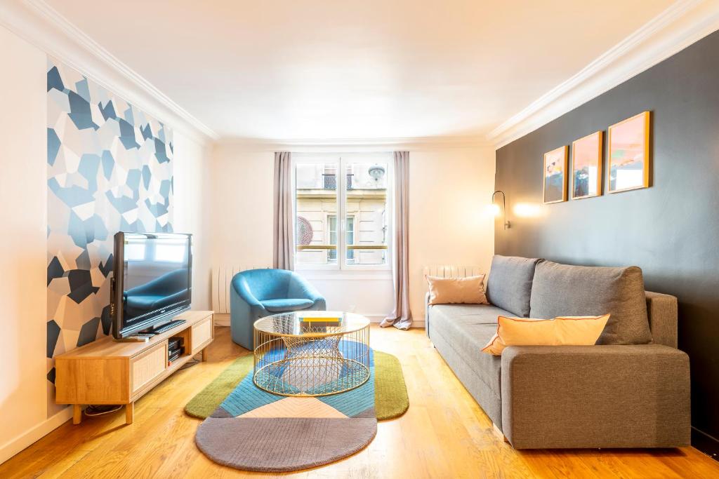 ein Wohnzimmer mit einem Sofa und einem TV in der Unterkunft HolidaysInParis - Bourg Tibourg in Paris