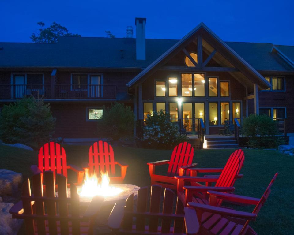 un grupo de sillas sentadas alrededor de un fuego frente a una casa en Minnewaska Lodge en Gardiner