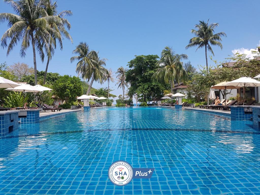 a large swimming pool at a resort with palm trees at Maehaad Bay Resort - SHA Plus in Mae Haad