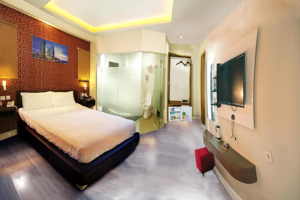 1 dormitorio con 1 cama y TV de pantalla plana en Antoni Hotel, en Yakarta