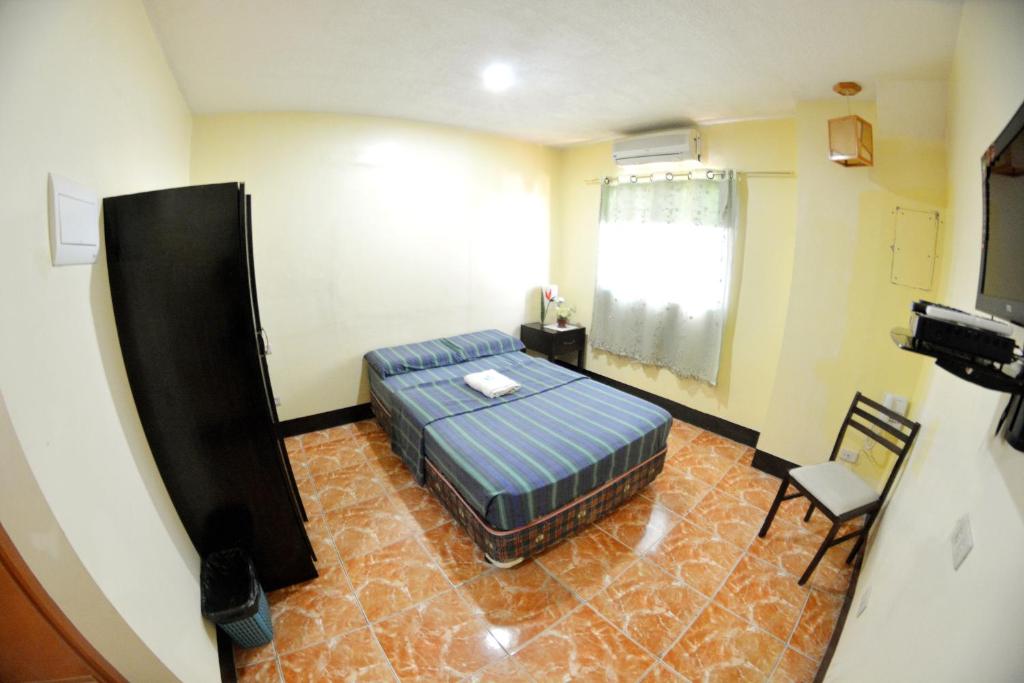 ein Schlafzimmer mit einem Bett und einem Stuhl in einem Zimmer in der Unterkunft Honey Hunt House in Cebu City