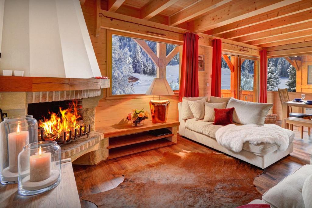 a living room with a fireplace in a log cabin at Chalet des Enfants La Clusaz - OVO Network in La Clusaz