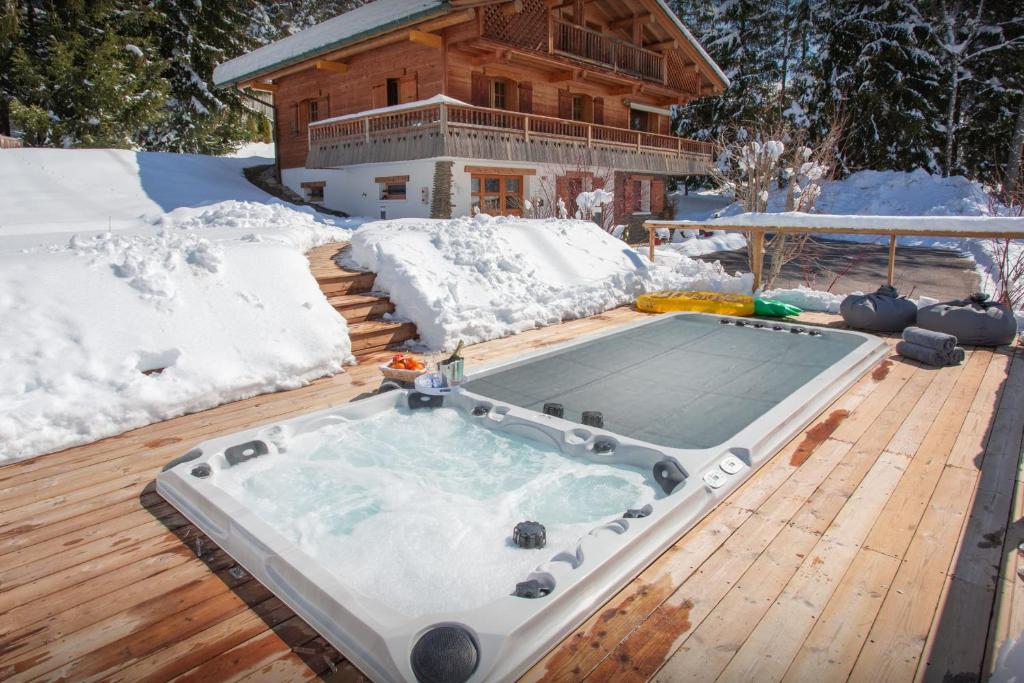 a hot tub on a deck in the snow at Chalet Le Mousqueton - OVO Network in La Clusaz