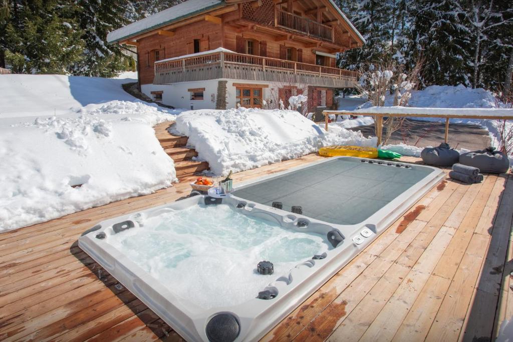 una bañera de hidromasaje en una terraza en la nieve en Chalet Le Mousqueton - OVO Network, en La Clusaz