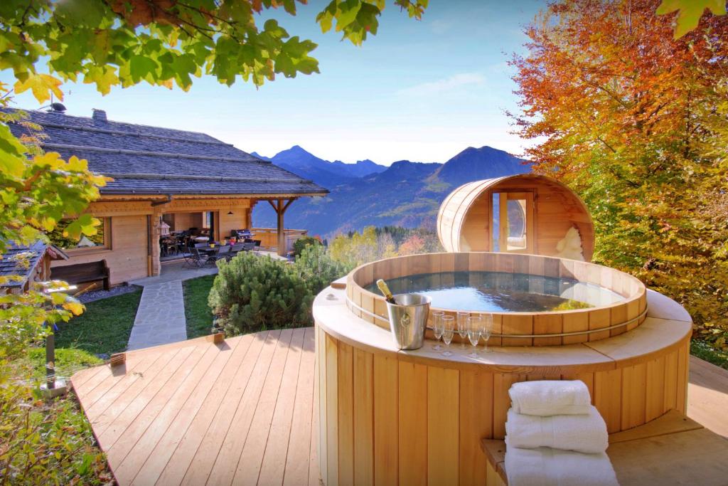 a hot tub on a deck with a house at La Grange à L'Ours - OVO Network in Manigod