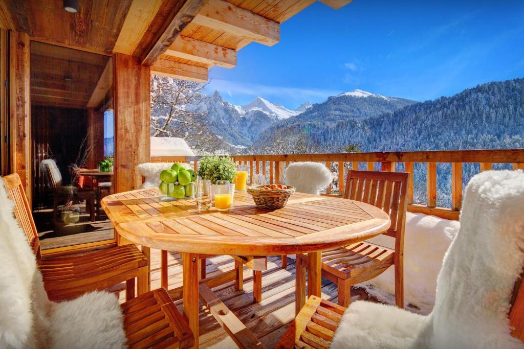 a wooden table on a balcony with a view of mountains at Chalet Les Brévins - OVO Network in Manigod