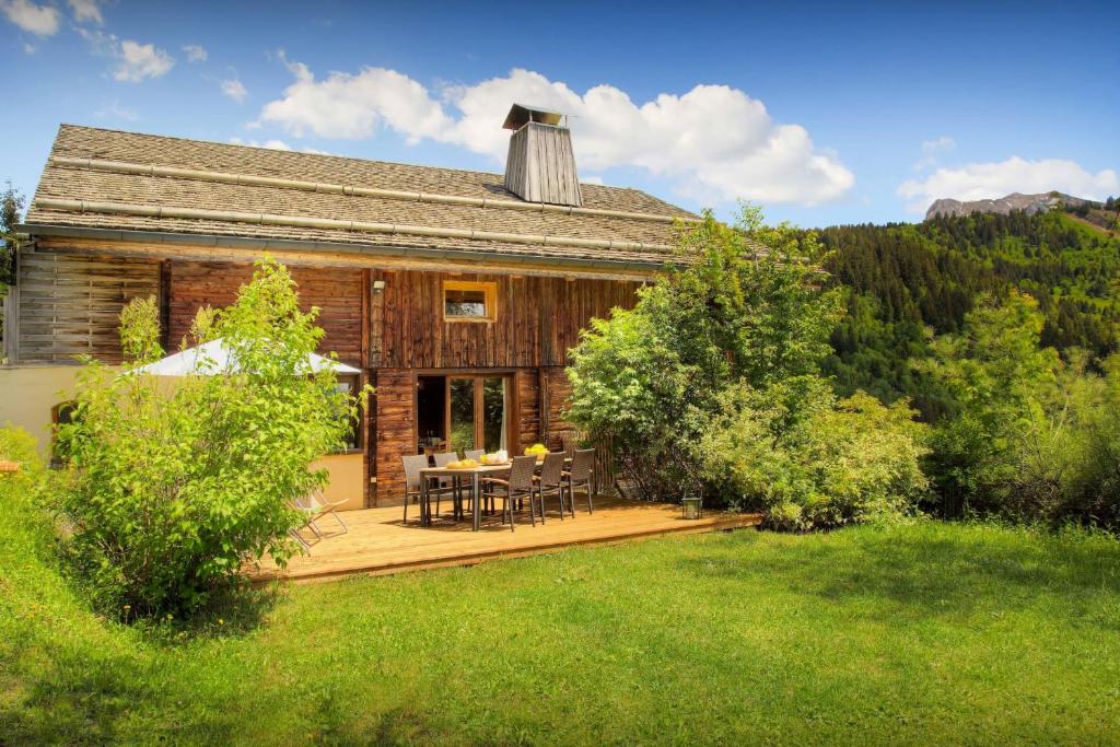 a log cabin with a table and chairs on a deck at Chalet Arsene et Lea - OVO Network in Manigod