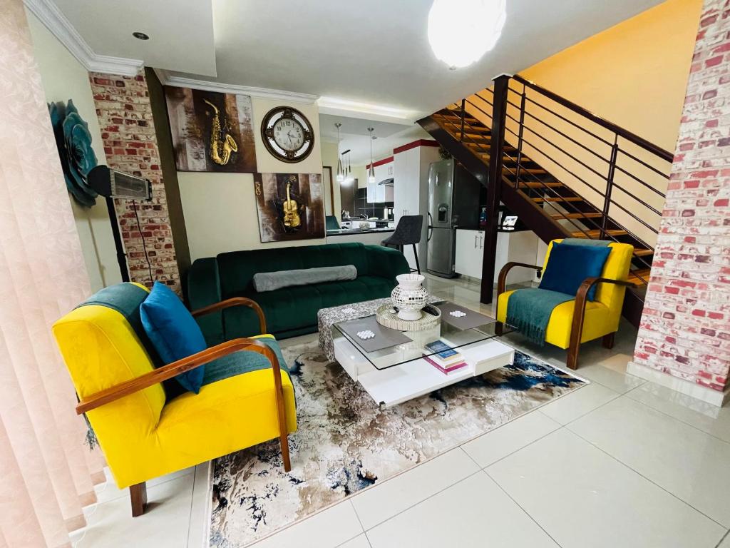 a living room with yellow and blue chairs and a table at Calm Modern and Cosy Stay in Polokwane