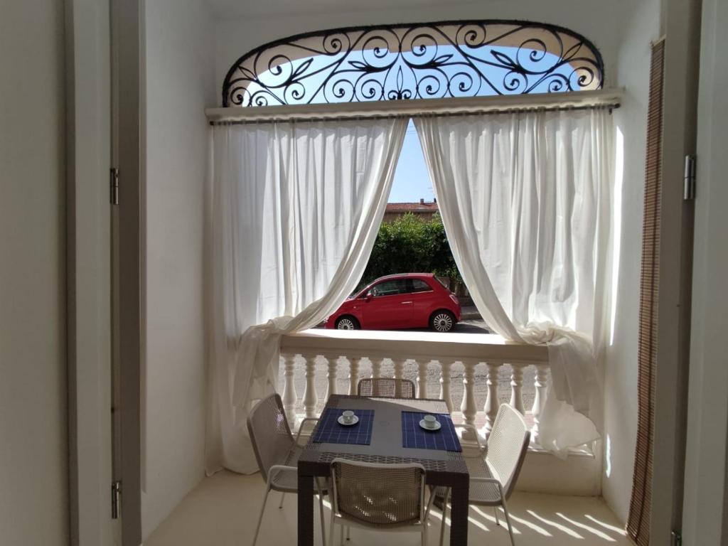ein Esszimmer mit einem Tisch und einem Fenster mit einem roten Auto in der Unterkunft Casa Cubino in Gioiosa Marea