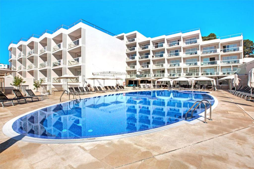 a swimming pool in front of a hotel at Aparthotel y Hotel Paguera Beach in Paguera