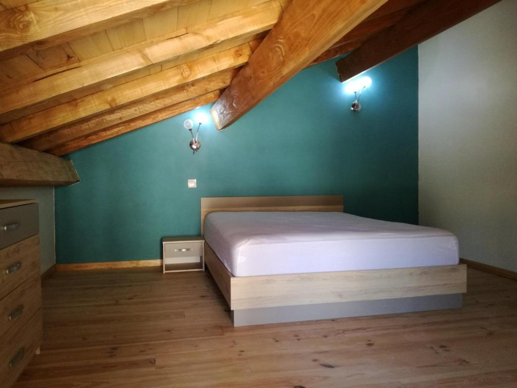 a bedroom with a bed with green walls and wooden ceilings at Gîte de caractère en pleine nature in Bourg-de-Visa