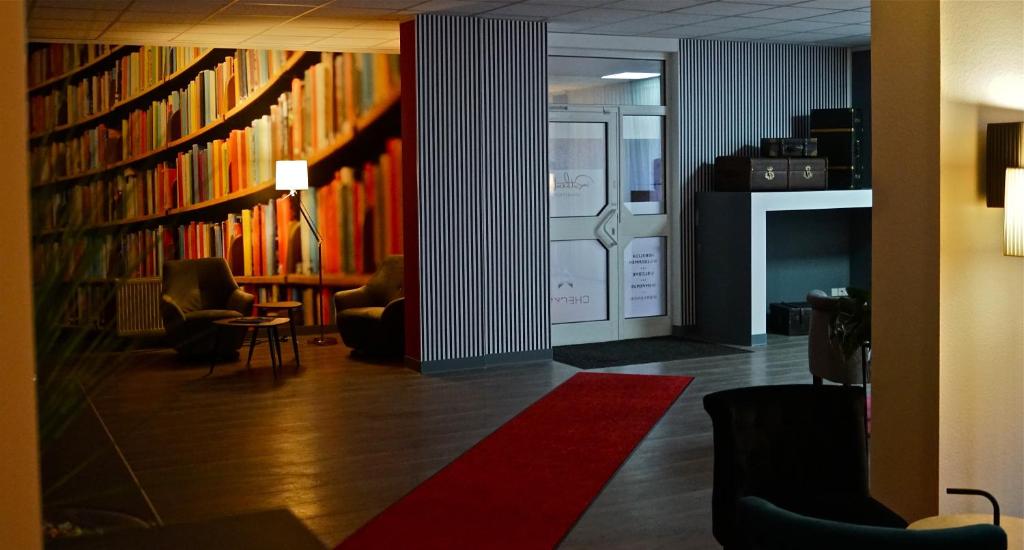 eine Bibliothek mit Bücherregalen und Stühlen sowie einem roten Teppich in der Unterkunft Rothenberger in Chemnitz