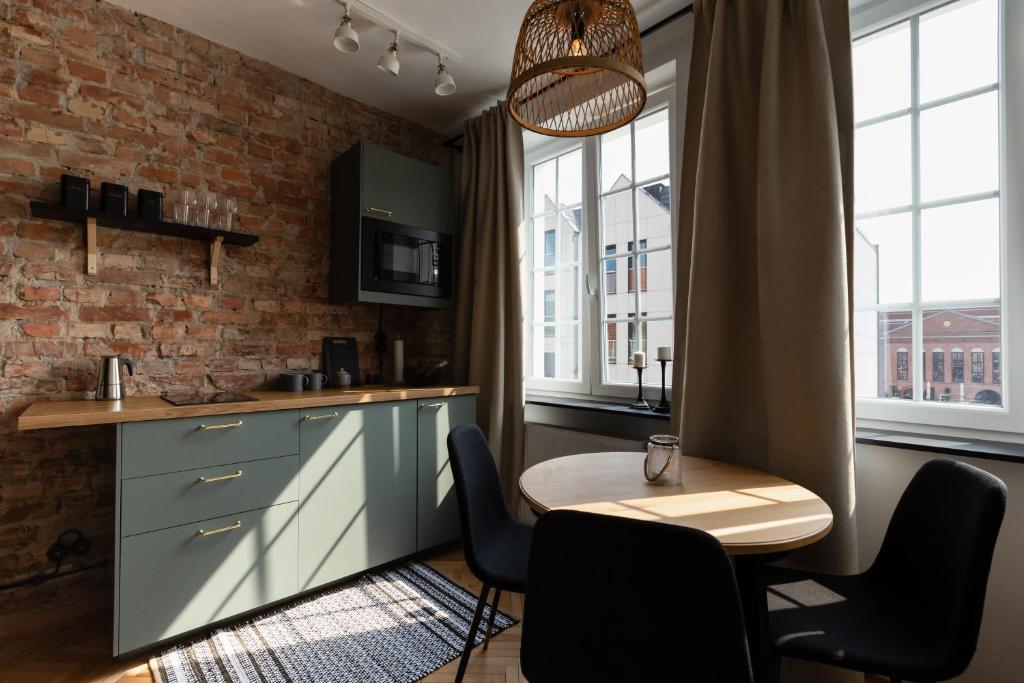 a kitchen with a table and chairs and a brick wall at Apartament nad Motławą in Gdańsk