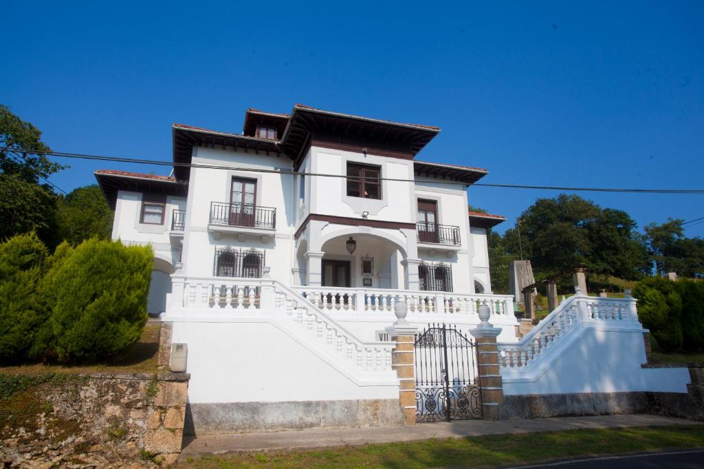 Dieses weiße Haus verfügt über einen Balkon und ein Tor. in der Unterkunft Villa Victoria in Vallobal