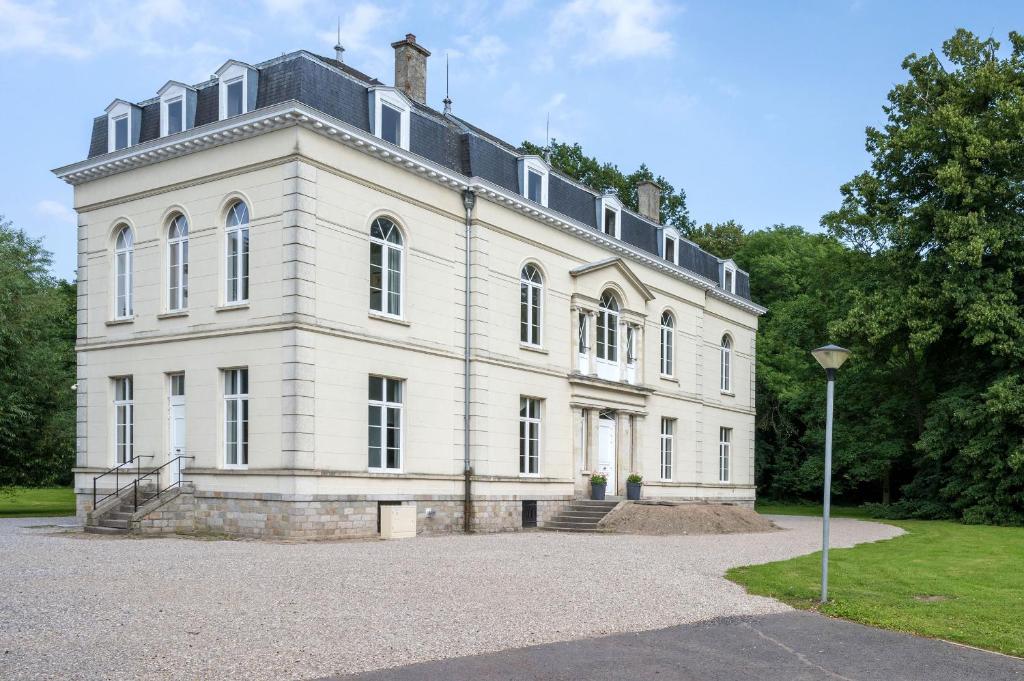 una gran casa blanca con árboles en el fondo en Chateau du Béron en Cappelle-en-Pévèle