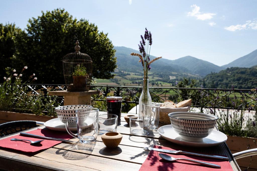 a table with plates and glasses on a table with a view at La Vieille Auberge in Vesc
