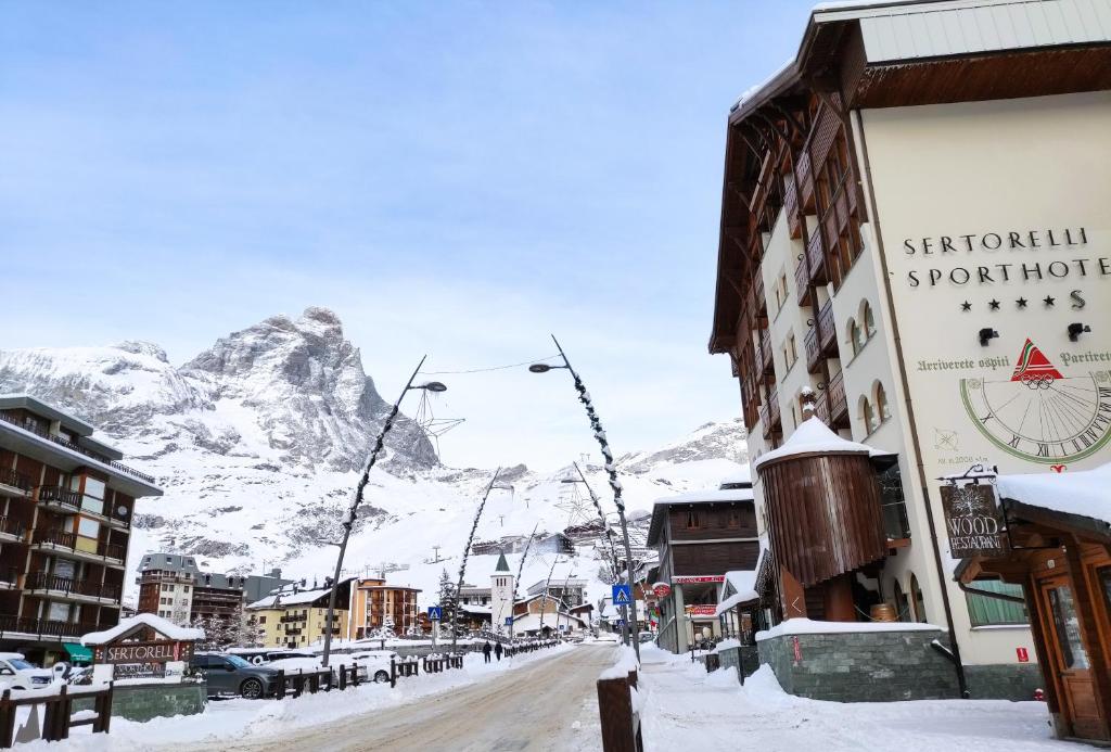 una calle cubierta de nieve con una montaña en el fondo en Sertorelli Sporthotel en Breuil-Cervinia