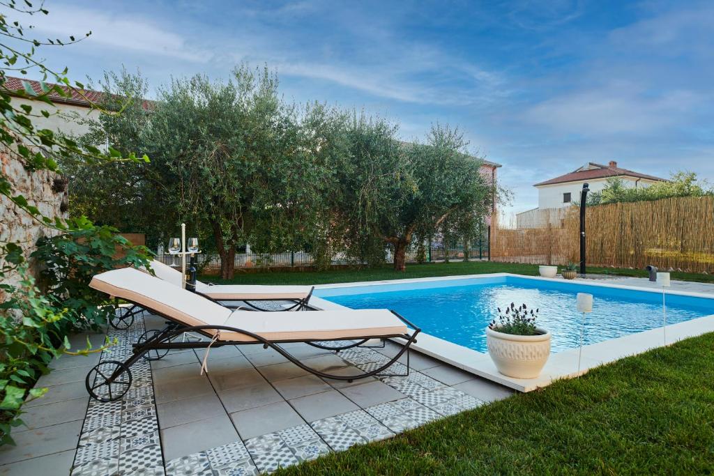 a swimming pool with a bench and a table in a yard at VILLA MEDITERANEA in Umag