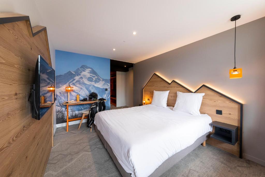 sypialnia z dużym białym łóżkiem i górskim malowidłem w obiekcie Hotel Base Camp Lodge - Les 2 Alpes w mieście Les Deux Alpes