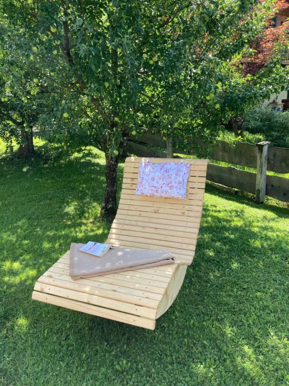 a wooden bench with a pillow sitting on the grass at Haus Schaffler in Kochel