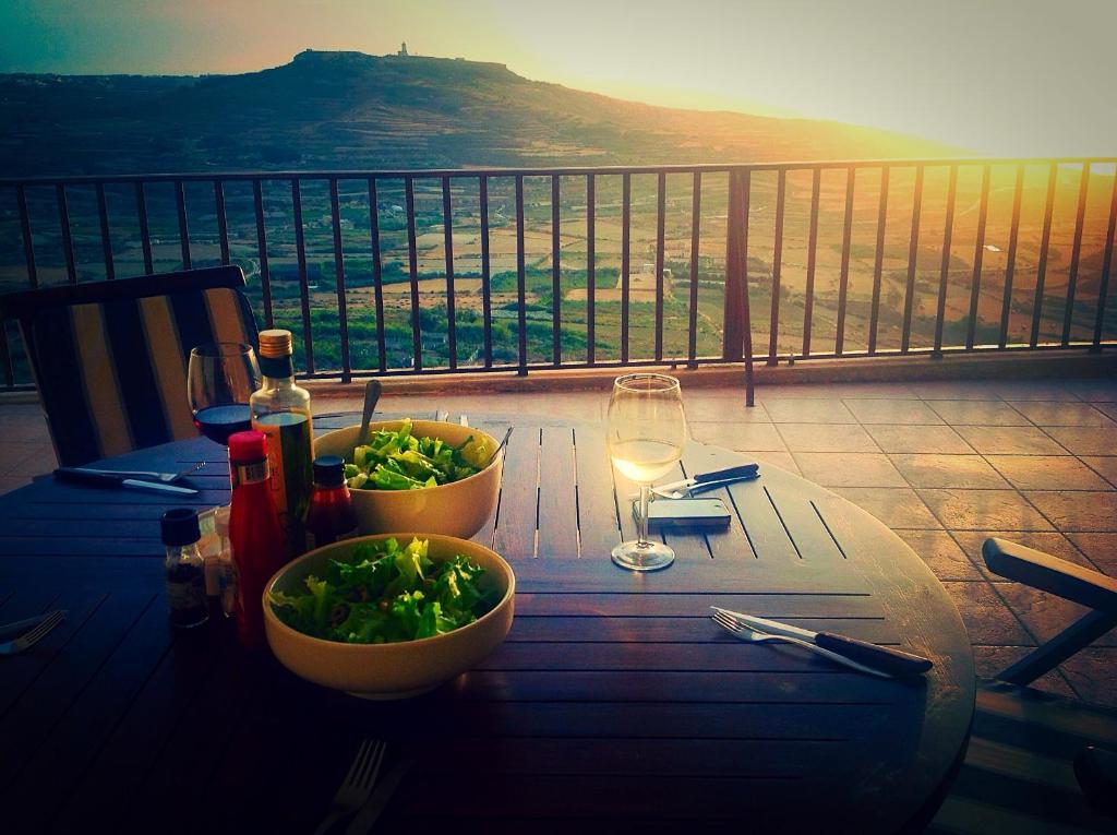 - une table avec un bol de salade et un verre de vin dans l'établissement The Heights 2 Bedroom Apartment, à Għasri