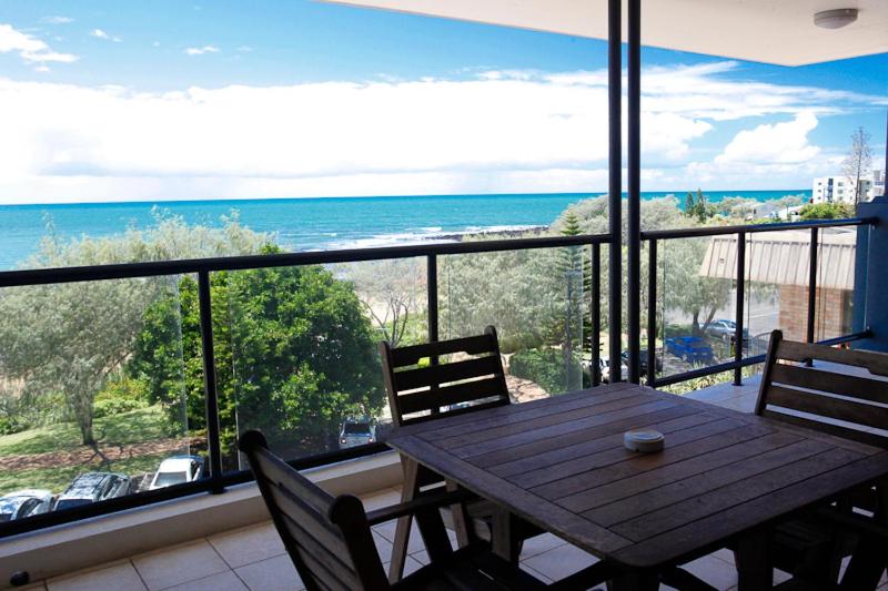 einen Tisch und Stühle auf einem Balkon mit Meerblick in der Unterkunft Pacific Reef by Kacys in Bargara
