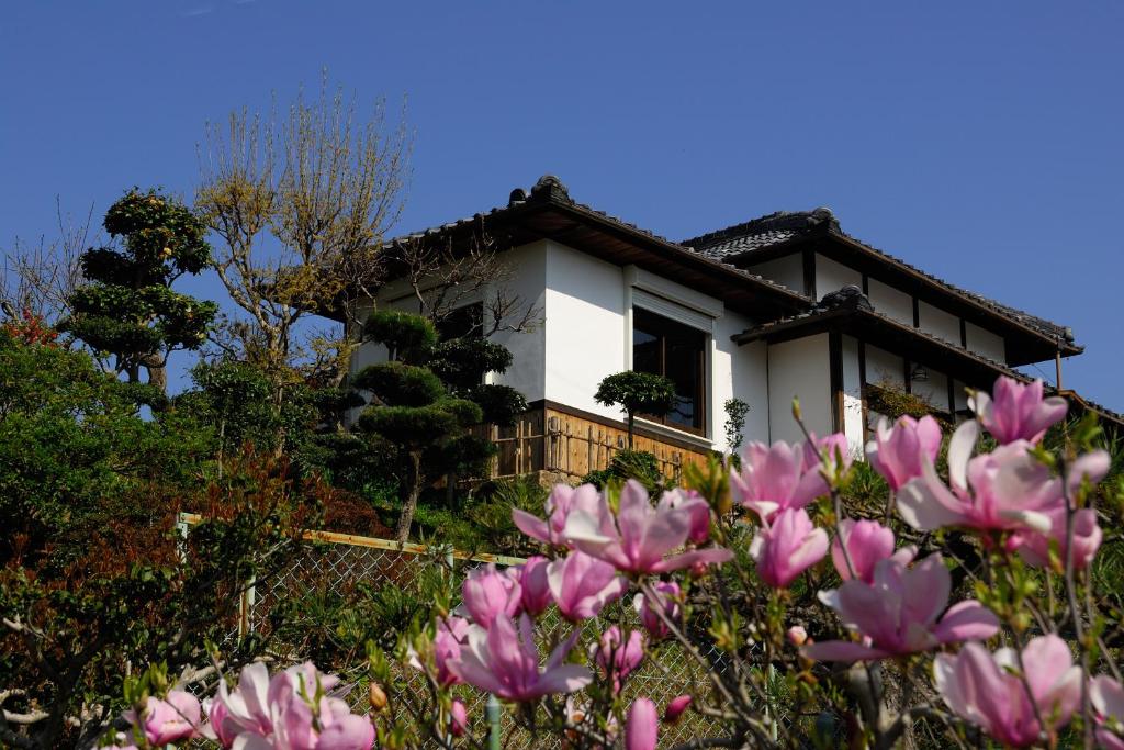 una casa con flores rosas delante de ella en Kotorian, en Asuka