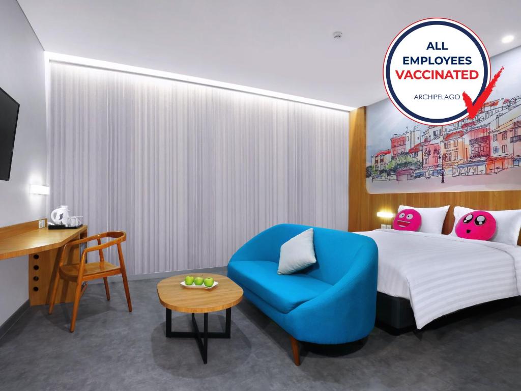 ケタパンにあるfavehotel Ketapangのベッドと青い椅子があるホテルの部屋