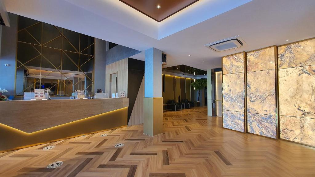 a lobby with a counter and wooden floors and a bar at Classie Hotel in Palembang